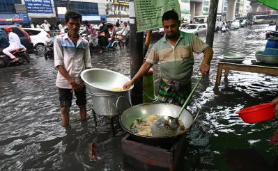 A vendor is preparing food in a submerged road as Dhaka experiences a sudden and continuous downpour for an hour in the afternoon causing waterlogging at Motijheel area in Dhaka on Wednesday, August 9, 2023. Photo: Dhaka Tribune