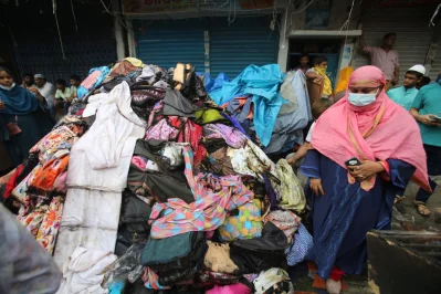 A woman stands beside goods brought out from a shop, damaged by fire that broke out at Mohammadpur Krishi Market on early Thursday, September 14, 2023. Photo: Mehedi Hasan/Dhaka Tribune