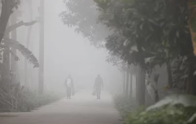 People walk on a road on a foggy winter morning in Louhajanj upazila of Munshiganj on Wednesday, January 3, 2023. Photo: Mehedi Hasan/Dhaka Tribune