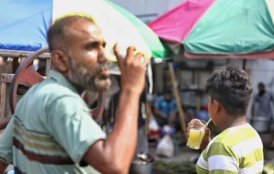 The image shows a man drinking sugarcane juice from a roadside shop in Dhaka to get relief from scorching heat. Photo: Ahadul Karim Khan/Dhaka Tribune