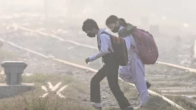 Schoolchildren wearing masks walk across a railway track amid thick smog in Lahore on November 20, 2024. Photo: AFP