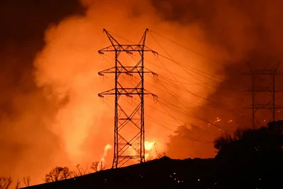 Flames and smoke are seen near power lines as the Palisades fire grows near the Mandeville Canyon neighborhood and Encino, California, on January 11, 2025. Photo: AFP