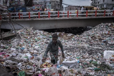 A man collecting shoes in southern Dhaka, where textile industries pollute the environment