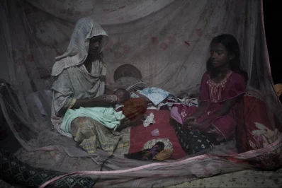 Mosammat Shirin, another slum resident, with her daughter and granddaughter inside a mosquito net at their home