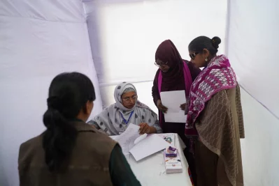A mock polling station for persons with disabilities, assisting a voter with visual disability.