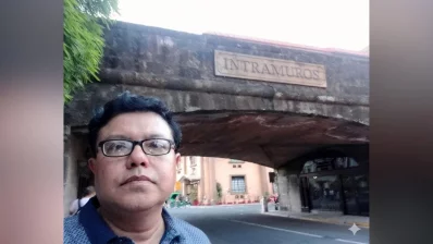 Writer standing in front of a historic arched gateway marked with a sign for Intramuros, the oldest district and historic core of Manila, the original fortified seat of government during the Spanish colonial period. The area is home to significant historical sites, including Fort Santiago, the Manila Cathedral, and the San Agustin Church. Photo: Dhaka Tribune/Collected
