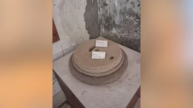A traditional stone grinding mill, known as chakki or jata, used historically for grinding grain into flour. It consists of two circular stones; the top stone (runner stone) rotates over a stationary bottom stone (bed stone) to crush grain. Grain is poured through the hole in the top stone, and a handle inserted into the smaller side hole is used to turn it. Photo: Dhaka Tribune