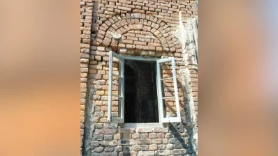 The window features a distinct arched top constructed from individual bricks, a technique used for both aesthetic appeal and structural support in older masonry. The open wooden window frames appear weathered and aged, due to time and neglect. Photo: Dhaka Tribune