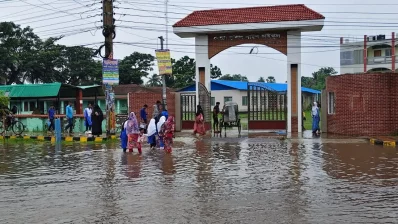 Students wade through a waterlogged road in front of a school in Khulna on Thursday, July 9, 2026. Photo: Dhaka Tribune