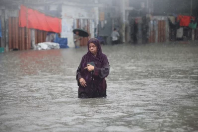An elderly pedestrian wades through a waterlogged street in the New Market area after heavy monsoon rain inundated parts of Dhaka on Sunday. Photo: Dhaka Tribune