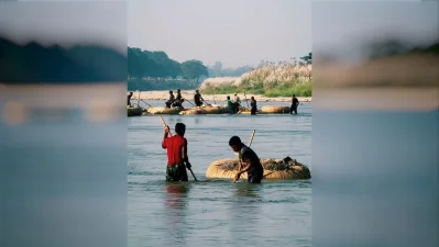 Traditional riverine stone quarrying along the Mahananda River in Tetulia. Laborers use distinctive round, tire-wrapped wicker basket rings. They dive or plunge long poles into the shallow riverbed to manually collect stones and sand drifting down from the Himalayas in India.