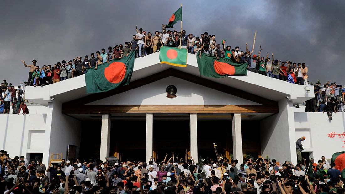 Anti-government protestors display Bangladesh`s national flag as they storm Sheikh Hasina`s office in Dhaka on August 5, 2024. Photo: AFP