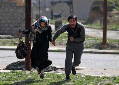 Iraqis run for cover as they flee Mosuls Al-Tayaran neighbourhood on February 28, 2017, during an offensive by Iraqi forces to retake the area from Islamic State fighters. Hundreds of civilians fled through the desert to escape fighting and privation in Mosul, joining thousands of others who left their homes as conditions worsen in the citys westrnrnAFP