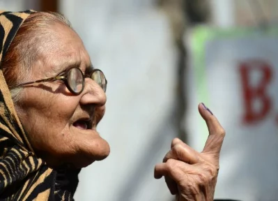 An Indian elderly woman displays an indelible ink mark on her finger after casting her vote at a polling station in Varanasi on March 8, 2017, during the last phase of the Uttar Pradesh state assembly electionsrnrnAFP