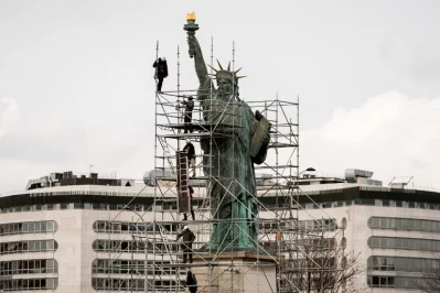 Workers stand on scaffolding erected around the Statue of Liberty replica by French sculptor Auguste Bartholdi (1834-1904) for renovation works on the Ile aux Cygnes in Paris on March 21, 2017, as the Maison de la Radio is seen in the backgroundrnrnAFP