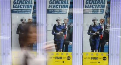 A woman walks past General Election themed posters with images of Britains Prime Minister Theresa May Britains main opposition Labour party leader Jeremy Corbyn in London on June 8, 2017, as Britain holds a general electionrnAFP