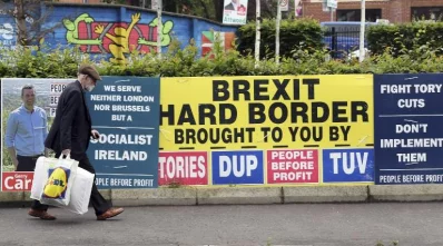 Pedestrians walk past election posters in west Belfast on June 8, 2017 as Britain votes in the general electionrnAFP