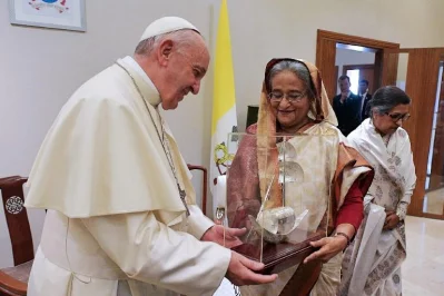 This handout picture taken and released by the Vatican press office (Osservatore Romano) on December 1, 2017 shows Pope Francis receiving a gift from Prime Minister of Bangladesh Sheikh Hasina during their meeting in Dhaka | AFP PHOTO / OSSERVATORE ROMANO