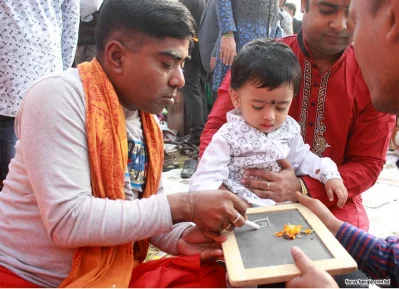 An infant is receiving Hate Khori (ceremonial inception of learning) in front of Saraswati, the deity of art and knowledge during the Saraswati Puja at Dhaka Universityu2019s Jagannath Hall on Monday. Hate Khori is one of the most significant parts of this celebration where Hindu children are taught their first word | Focus Bangla