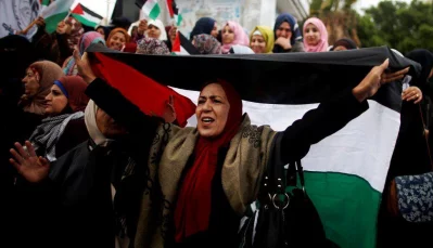 A woman holds a Palestinian flag during a protest against the US intention to move its embassy to Jerusalem and to recognize the city of Jerusalem as the capital of Israel, in Gaza City December 6, 2017 (REUTERS)