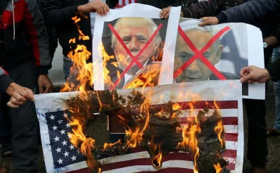 Palestinians burn posters depicting Israeli Prime Minister Benjamin Netanyahu and US President Donald Trump during a protest against the US intention to move its embassy to Jerusalem and to recognize the city of Jerusalem as the capital of Israel, in Rafah in the southern Gaza Strip December 6, 2017 (REUTERS)