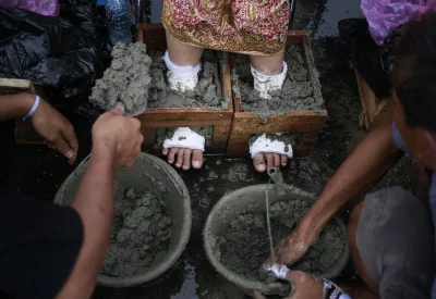 In this March 20, 2017 photo, a woman from Kendeng, Central Java whose feet are encased in concrete waits for assistance to step off a truck upon arrival for a rally against the operation of a cement factory in the region, outside the presidential palace in Jakarta, IndonesiarnrnAP