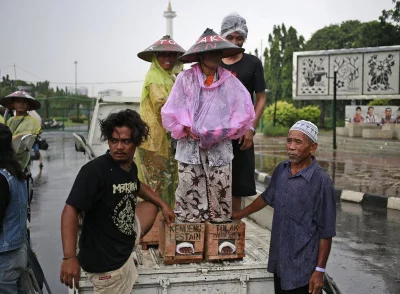 In this March 20, 2017 photo, protesters whose feet are encased in concrete wait for assistance to step off a truck upon arrival for a rally against the operation of a cement factory in Kendeng, Central Java, outside the presidential palace in Jakarta, Indonesia. Kendeng farmers have battled against plans for the factory for years, saying it could taint their water. The factory is now more or less complete and the owner, state-owned PT Semen Indonesia, has said it would create jobs and boost the local economyrnrnAP