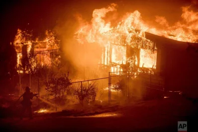 A firefighter sprays water as flames from a wildfire engulf a residence near Oroville, Calif, on Sunday, July 9, 2017. Evening winds drove the fire through several neighbourhoods levelling homes in its pathrnrnAP
