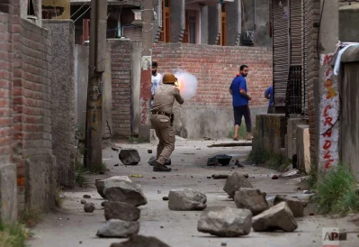 An Indian police officer fires a teargas shell to disperse Kashmiri protesters after the funeral of local rebel Aqib Ahmad in Srinagar, Indian controlled Kashmir, Wednesday, July 12, 2017. Anti-India protests and clashes erupted in the main city in Indian-controlled Kashmir after three men police identified as Kashmiri rebels were killed in a gun battle with government forcesrnrnAP