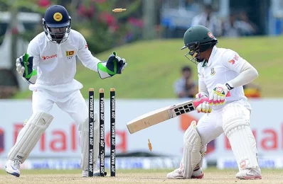 Bangladesh cricket captain Mushfiqur Rahim (R) looks back towards his wicket after being dismissed by unseen Sri Lankan spinner Rangan Herath as wicketkeeper Niroshan Dickwella looks on during the third day of the opening Test cricket match between Sri Lanka and Bangladesh in Galle on March 9, 2017/AFP PHOTO