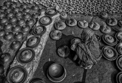 A woman sets down one of the pots, among the thousands of pots | Photo: Zahidur Rahman