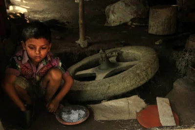A child crouches near the pottery wheel | Photo: Zahidur Rahman