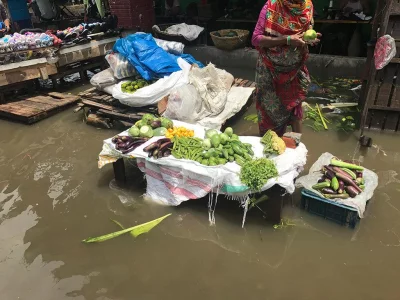 Street hawkers, forced by necessity to continue working in the water, are in a constant battle to keep their wares dry. Photo: MD FAZLUR RAHMAN/DHAKA TRIBUNE