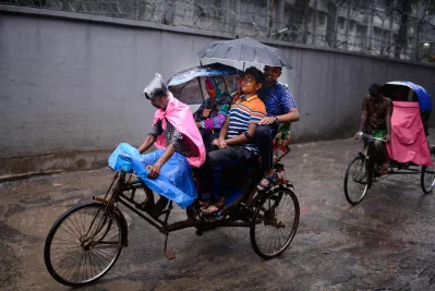Its very difficult to commute in rain, let alone find a transportation. Even then, there is no stopping people from getting to places. A rickshaw puller takes three passengers as they struggle to cover themselves from rain  | Mahmud Hossain Opu