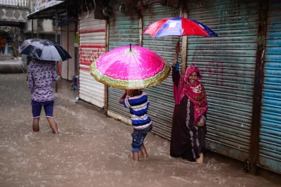 A woman smiles as she tries to walk in the pouring rain  | Mahmud Hossain Opu