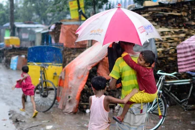 A man carries his child on his back as he holds an umbrella  | Mahmud Hossain Opu