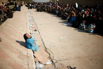A displaced Iraqi woman reacts as she waits in a street for a truck to carry her to a safe place, as Iraqi forces battle with Islamic State militants, in western MosulrnrnREUTERS