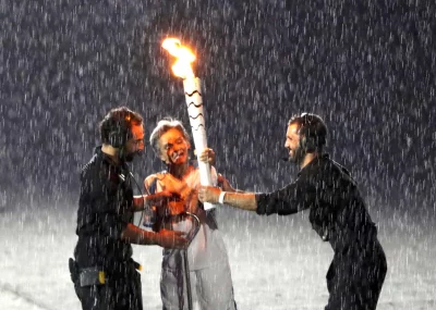 Brazilian Paralympic runner Marcia Malsar is assisted after falling while carrying the torch as rain falls during the opening ceremony