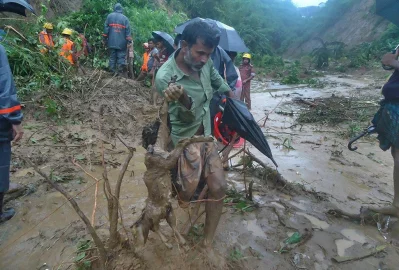 A man carries the carcass of a goat as rescuers search amid the mud after a landslide in Bandarban, Bangladesh, Tuesday, June 13, 2017 Associated Press