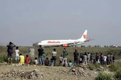 Onlookers watch Nepali workers trying to bring a Malaysian airliner back onto the runway at the international airport in Kathmandu on April 20, 2018, after it skidded off the runway following an aborted take-off | AFP