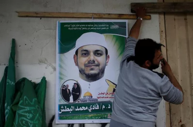 A man hangs a poster depicting Palestinian electrical engineer Fadi al-Batash, who was shot to death in Malaysia, on his family house in the northern Gaza Strip April 21, 2018 | Reuters