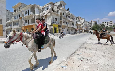Syrian children ride on a horse past destroyed buildings as they celebrate the first day of the Muslim Eid al-Fitr holiday | AFP
