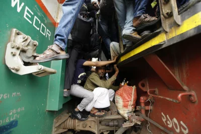 People stand or sit precariously between two compartments of a train, the day before Eid-ul-Fitr, as they leave Dhaka for the holiday Mahmud Hossain Opu