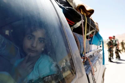 A Syrian refugee girl who left Lebanon looks through a window as she arrives in Qalamoun, Syria | Reuters