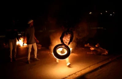 A man blocks a road with a burning tire while protesting against electricity cuts in Klipspruit Soweto, Johannesburg, South Africa | Reuters