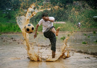 A man kicks a ball as he takes part in an event celebrating National Paddy Day, also called Asar Pandra, marking the commencement of rice crop planting in paddy fields as monsoon season arrives, in Lalitpur, Nepal | Reuters