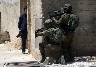 A photographer takes cover as Israeli forces stand behind a wall during clashes with Palestinian demonstrators  AFP