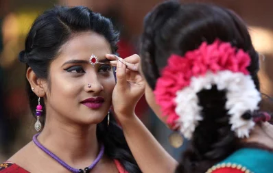 A woman applies makeup on a performeru2019s forehead, in preparation of the Pohela Falgun event being celebrated at Charukola, Dhaka University, on February 13, 2019 | Syed Zakir Hossain