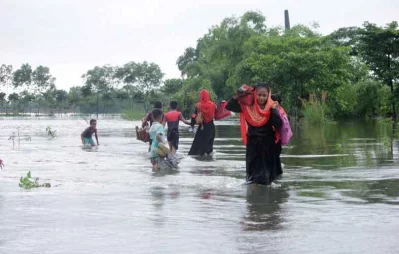 Children and women walking in knee-deep water as flash floods and rainfall inundated low-lying areas in Gowainghat upazila of Sylhet Asmot Aovi