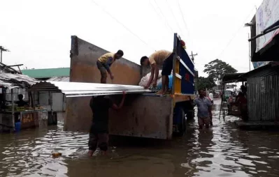 Some men are unloading house building materials from a truck that got stuck in water after rain in Sunamganj Himadri Shekhar Bhadra/ Dhaka Tribune